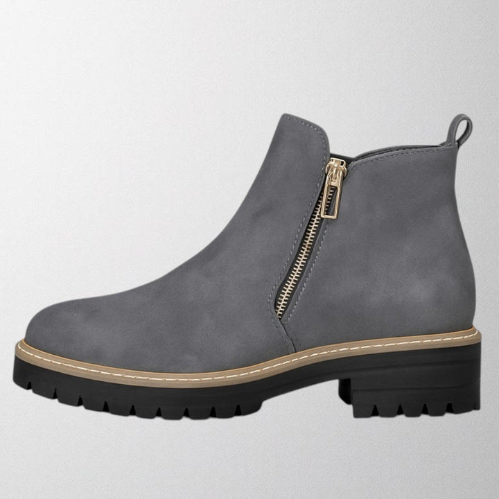 Black ankle boots for women featuring a stylish gold zip, chunky lug sole, and soft suede upper for a comfortable fit. 1
