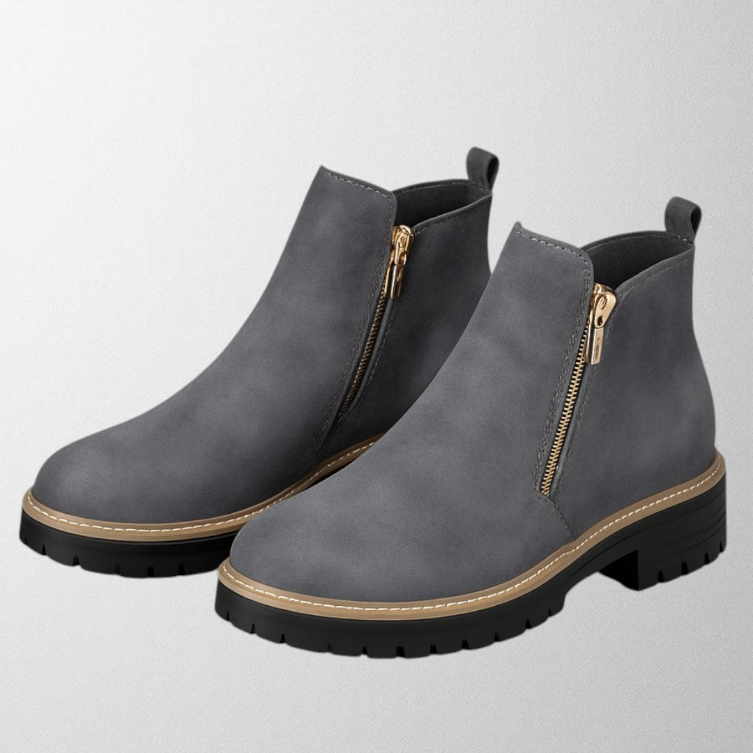 Black ankle boots for women featuring a stylish gold zip, chunky lug sole, and soft suede upper for a comfortable fit. 7