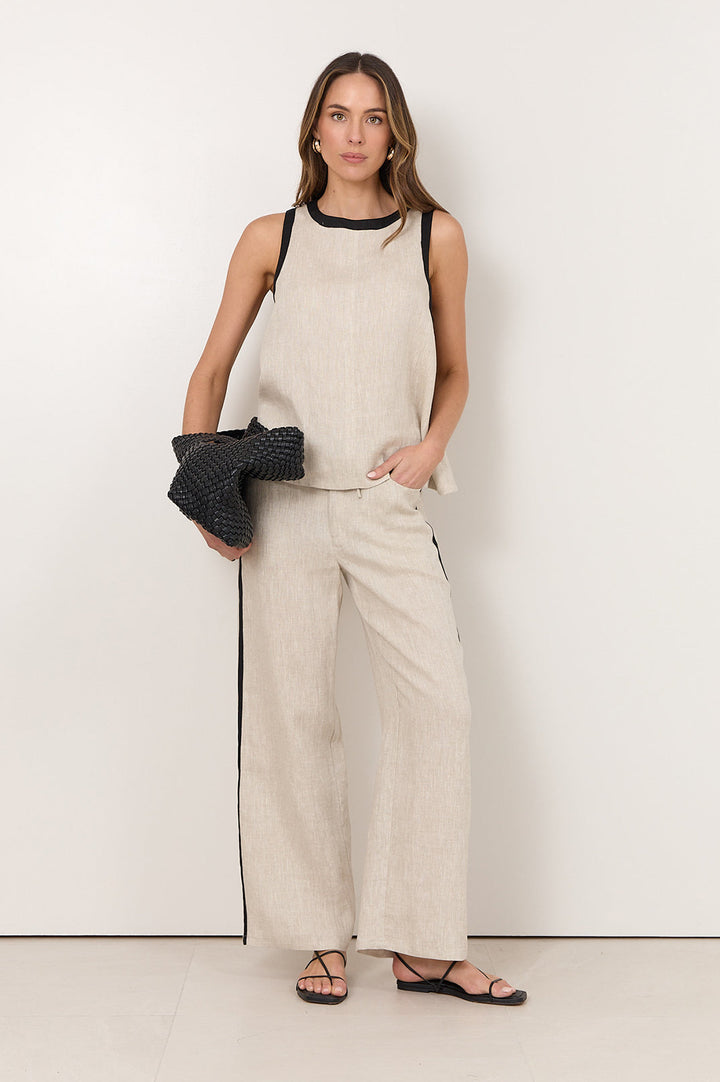 Linen pants for women featuring an elastic waistband, side pockets, and a natural straight-leg design accented with black trim. 0