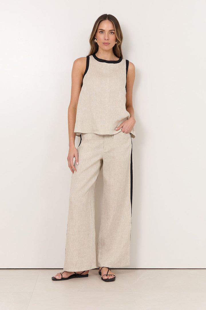 Linen pants for women featuring an elastic waistband, side pockets, and a natural straight-leg design accented with black trim. 2