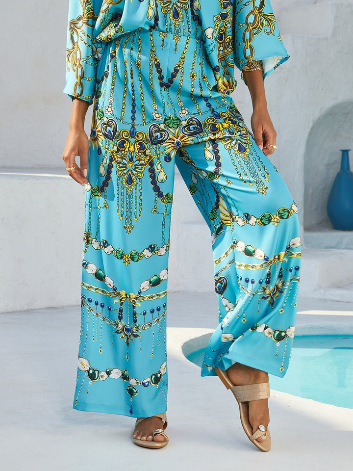 Silky satin women's pants in Mediterranean blue featuring a gold-chain print and an elastic waistband, designed in a stylish straight-leg cut. 0