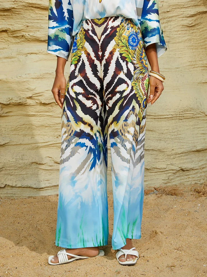 Silky satin women's pants in Mediterranean blue featuring a gold-chain print and an elastic waistband, designed in a stylish straight-leg cut. 11