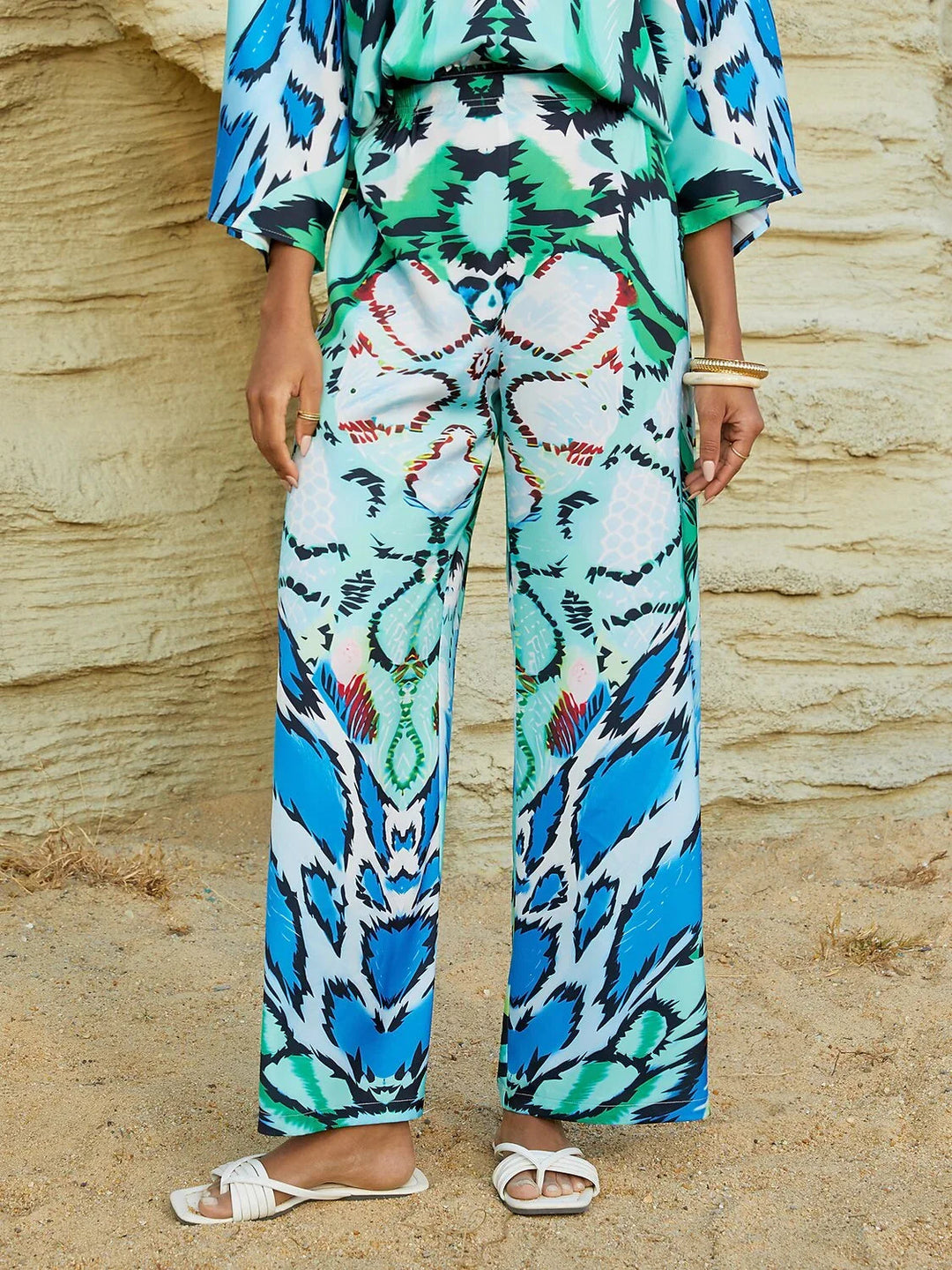 Silky satin women's pants in Mediterranean blue featuring a gold-chain print and an elastic waistband, designed in a stylish straight-leg cut. 15