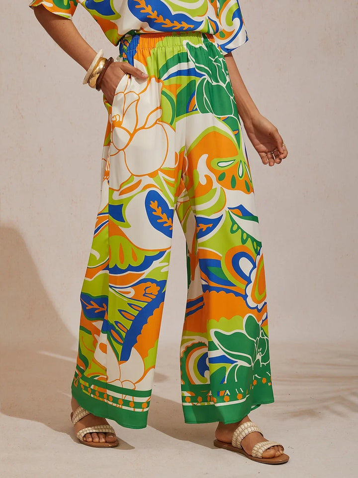 Silky satin wide leg pants featuring an elastic waist and vibrant tropical print, designed for a flowy relaxed fit for women. 17