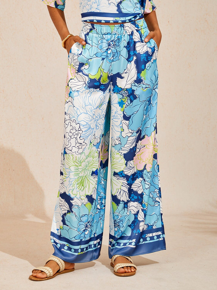 Wide leg pants for women made of silky satin featuring an elastic waist and a floral design in cream and yellow. 11