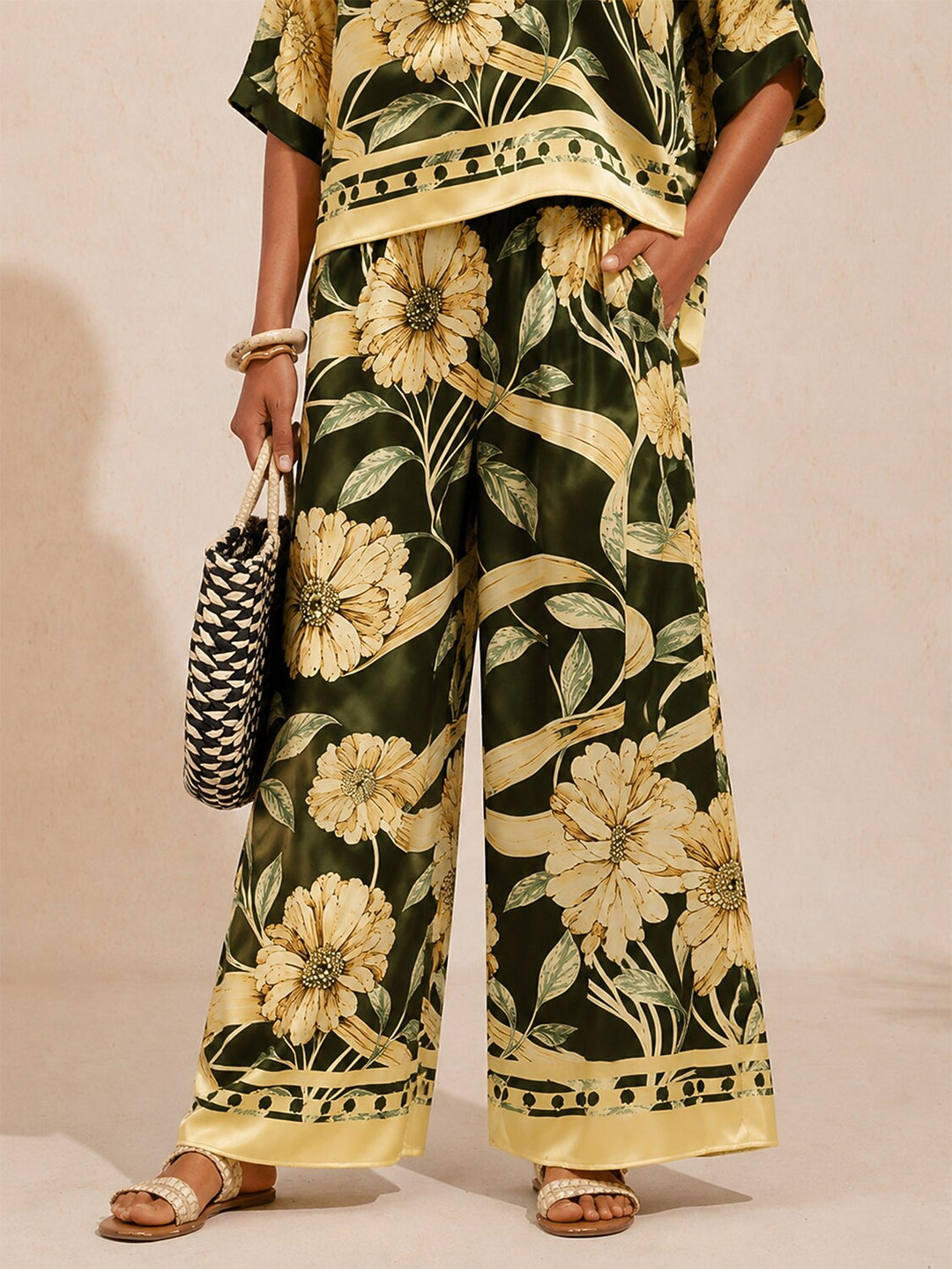 Wide leg pants for women made of silky satin featuring an elastic waist and a floral design in cream and yellow. 2