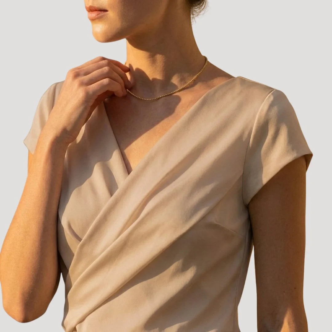Elegant white women's blouse featuring a draped V-neck and short sleeves, perfect for summer styling.

 3