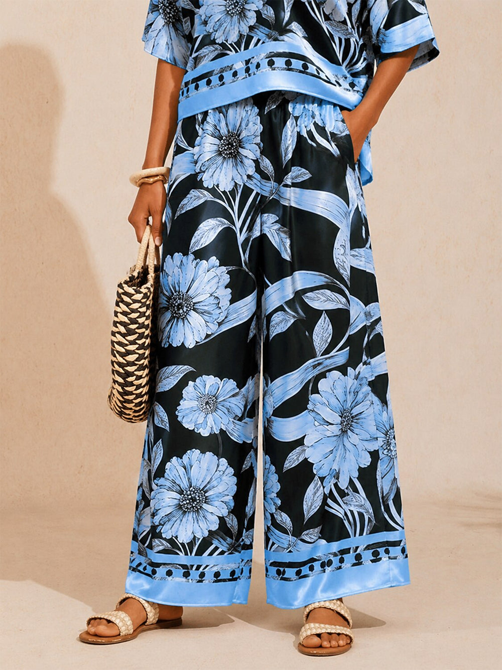 Women's wide-leg pants featuring an elastic waist and convenient pockets, designed with a beautiful floral satin pattern in glacier blue. 1
