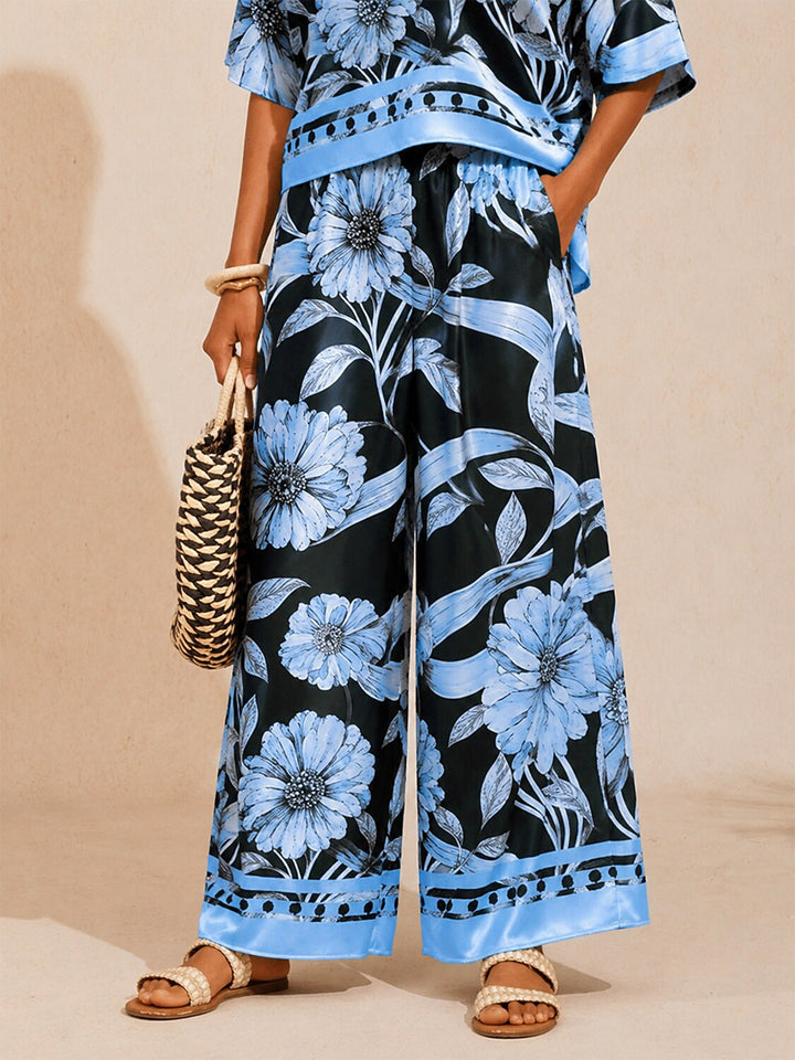 Women's wide-leg pants featuring an elastic waist and convenient pockets, designed with a beautiful floral satin pattern in glacier blue. 1
