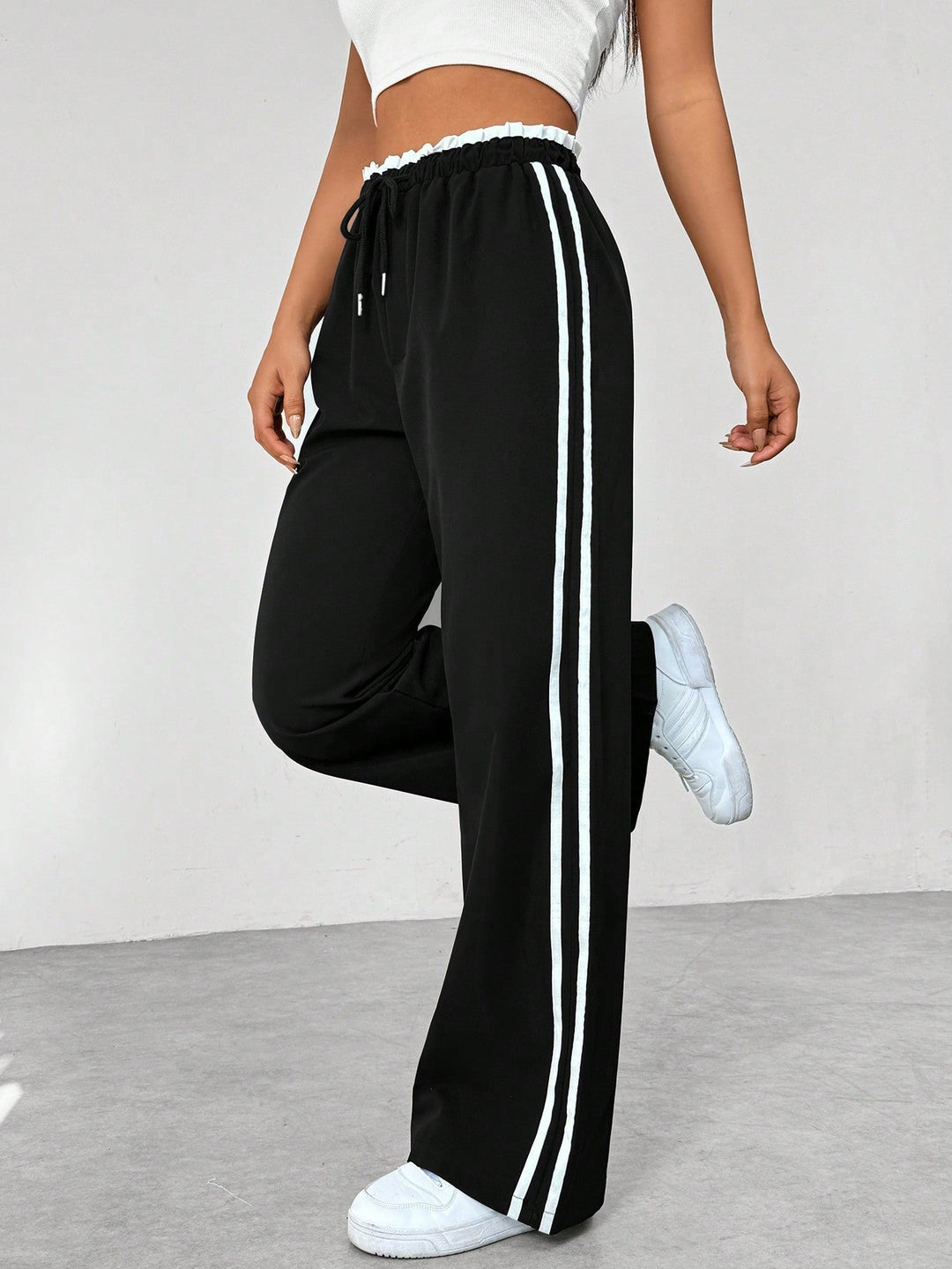 Women's wide leg trousers featuring an adjustable drawstring waist, sporty side stripes, and a lightweight design for a casual and comfortable look. 2