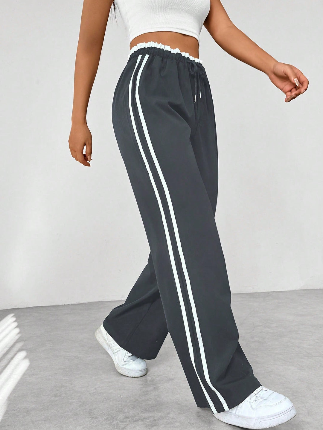 Women's wide leg trousers featuring an adjustable drawstring waist, sporty side stripes, and a lightweight design for a casual and comfortable look. 3
