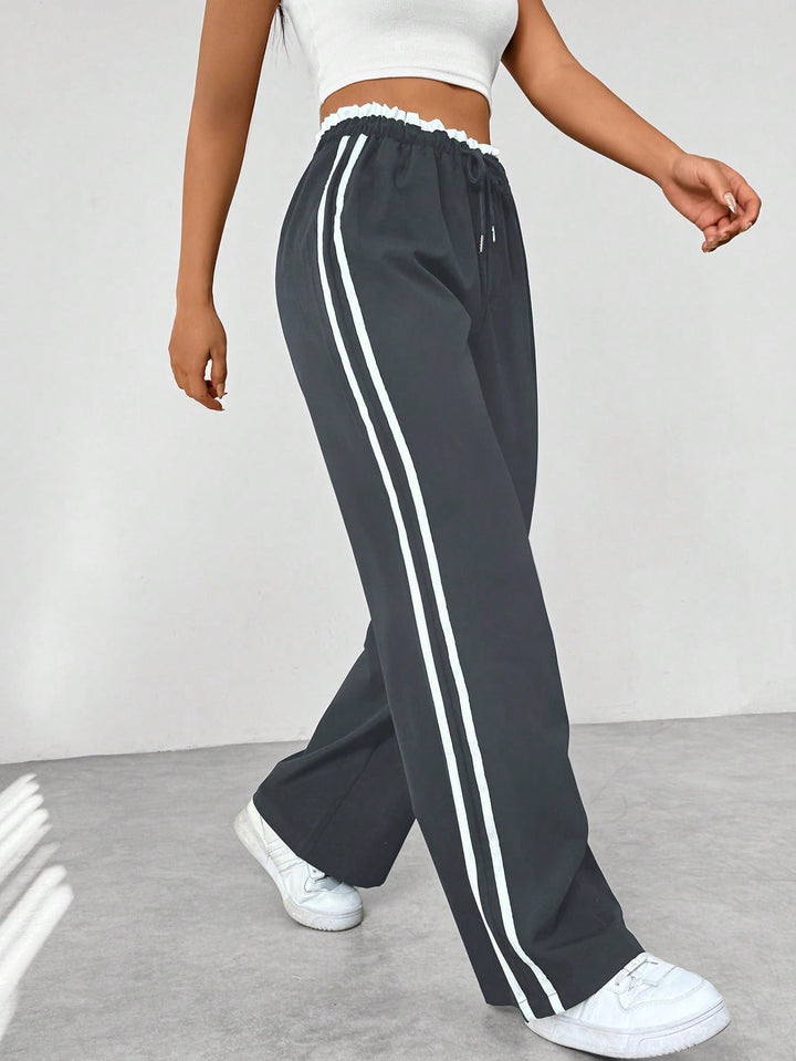 Women's wide leg trousers featuring an adjustable drawstring waist, sporty side stripes, and a lightweight design for a casual and comfortable look. 3