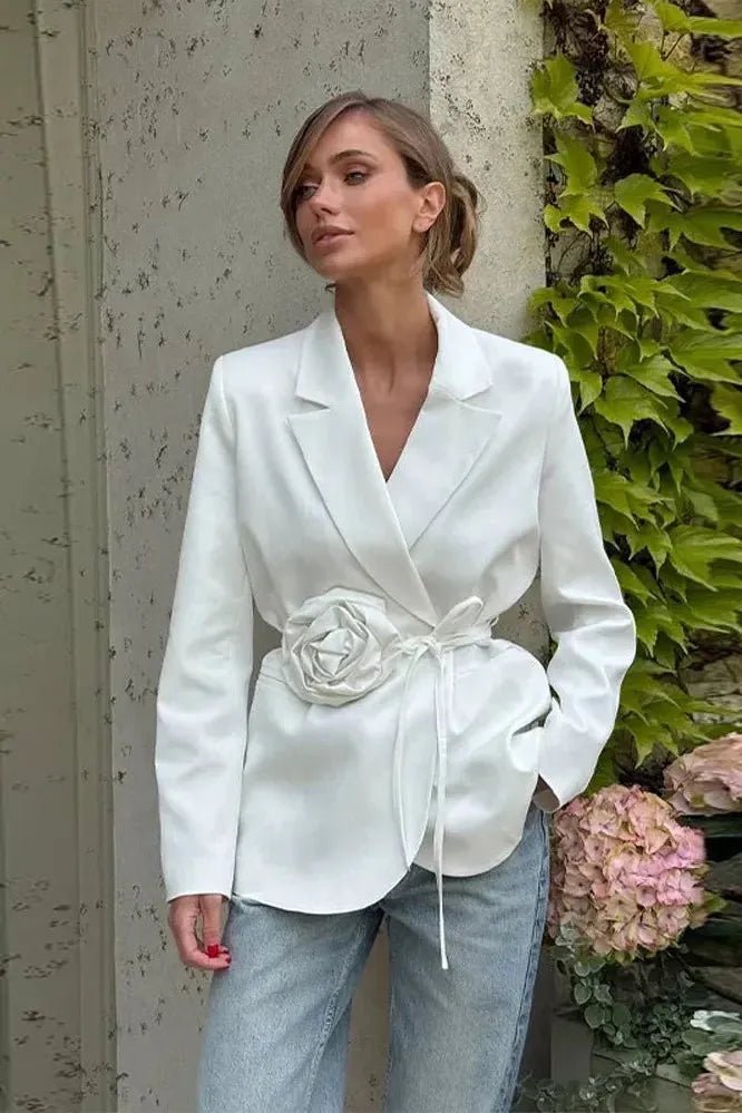 Elegant women's wrap blazer in white featuring an adjustable self-tie belt and delicate rosette appliqué, perfect for sophisticated occasions. 0