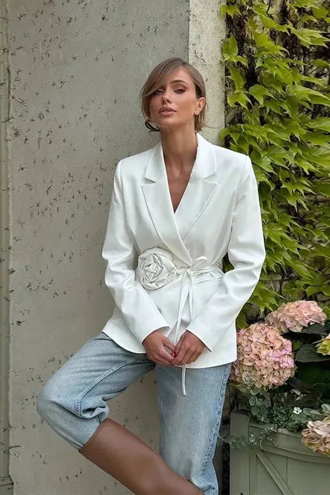 Elegant women's wrap blazer in white featuring an adjustable self-tie belt and delicate rosette appliqué, perfect for sophisticated occasions. 1