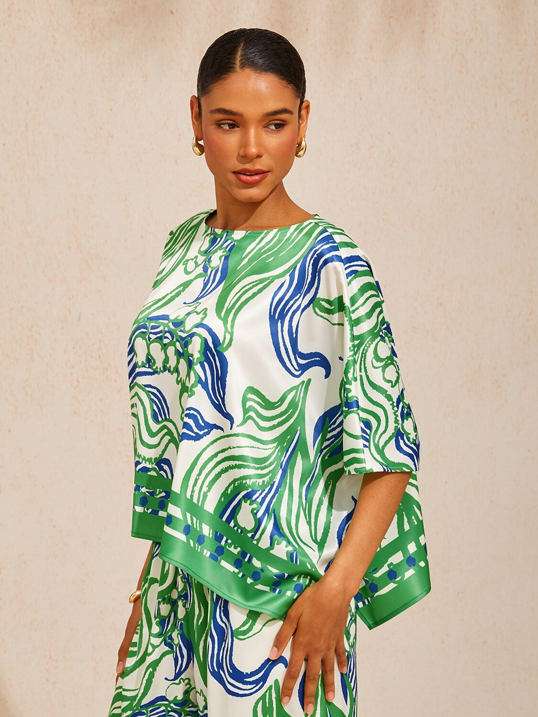 Womens top featuring an asymmetric hem and batwing sleeves in an abstract floral satin design, perfect for stylish and comfortable everyday wear. 2