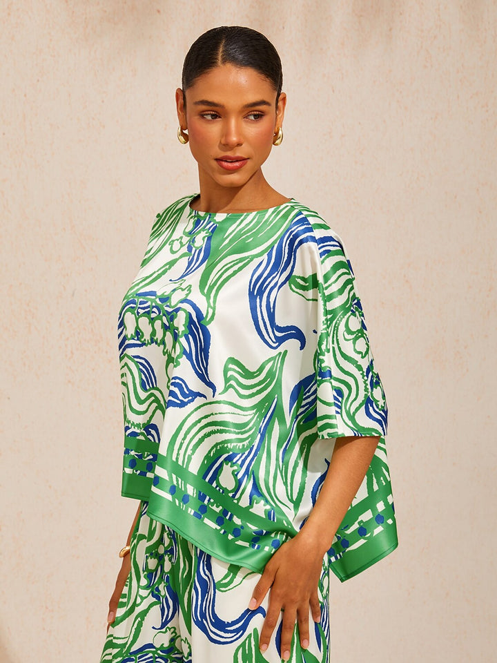 Womens top featuring an asymmetric hem and batwing sleeves in an abstract floral satin design, perfect for stylish and comfortable everyday wear. 2